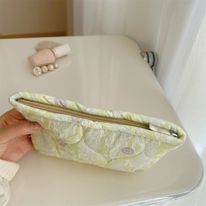 Quilted floral makeup bag held in hand showing the top opening and soft fabric texture