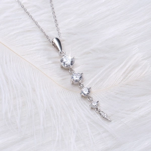 Macro shot of S925 silver necklace with vertical round zircons on white feather background