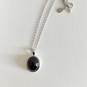 Close-up of a 925 sterling silver puzzle necklace with a black oval gemstone pendant