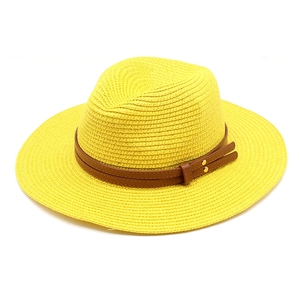 Détail d'un chapeau de paille jaune avec ruban en cuir brun et rivets dorés