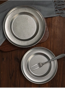 Flat lay of retro stainless steel pasta plates and fork on dark wooden background