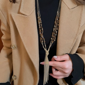 Close-up of elegant long beaded necklace with amber crystals and gold metal fringe tassel