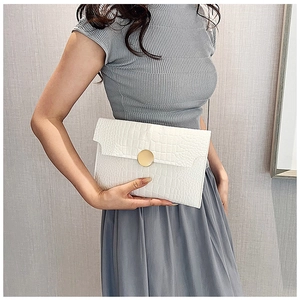 Close-up of white crocodile pattern envelope clutch bag with gold round metal buckle