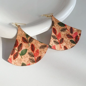 Detailed close-up of cork texture fan-shaped earrings with red and green leaf patterns