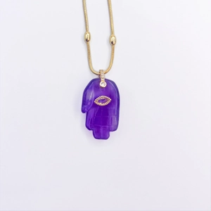 Primer plano del collar con colgante de mano de Hamsa en piedra púrpura y ojo dorado
