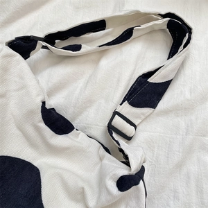 Detail of corduroy cow print bag featuring adjustable strap and black plastic buckles