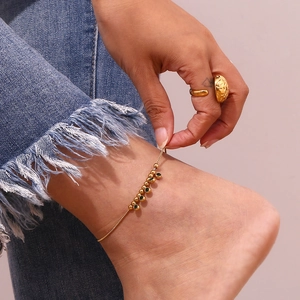 Detail of 18K gold plated stainless steel anklet with green diamond charm on model