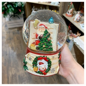 Detailed view of a Christmas snow globe music box with Santa and snowman relief base
