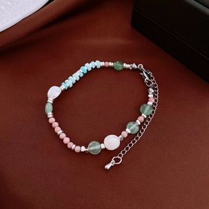 Détail du collier de perles en pierres naturelles et fermoir argenté sur tissu texturé