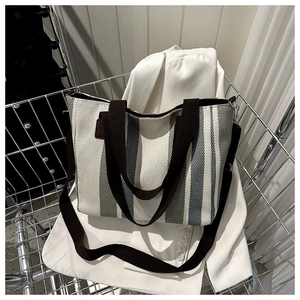 Detail of striped canvas tote bag with brown straps inside a metal shopping cart