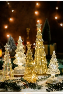 Illuminated glass Christmas trees with wooden bases and warm LED glow for holiday decor