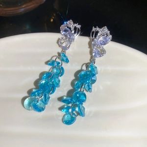 Gros plan de boucles d'oreilles papillon avec perles de cristal bleu sur plateau céramique