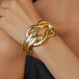 Close-up of a chunky twisted gold bangle featuring a glossy pleated texture on a wrist