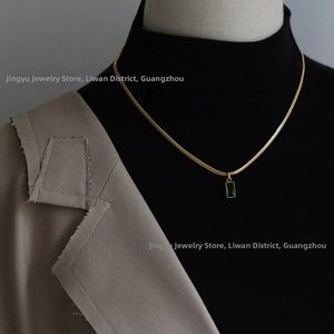 Chaîne serpent dorée 18K chic avec pendentif rectangulaire vert émeraude sur blazer