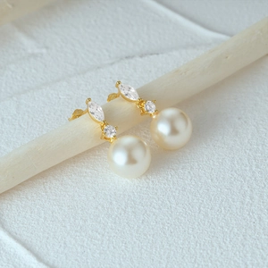 Macro detail of S925 silver pearl earrings with marquise zircon and golden finish