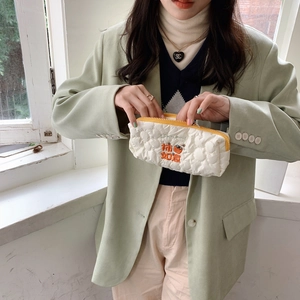 Close-up of quilted white pencil case with persimmon embroidery and zipper closure