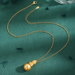 Golden pearl necklace with Monkey King zircon pendant on dark green background
