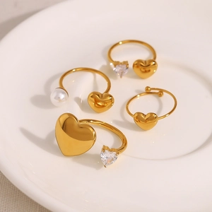 Four-piece gold stainless steel ring set featuring heart shapes, pearls, and zircons
