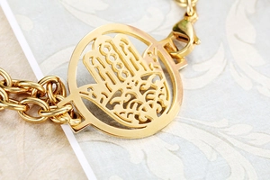 Macro view of gold Hamsa hand pendant and double layer chain with lobster clasp detail