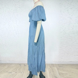 Detail of light blue off-shoulder maxi dress with puff sleeves and pleated tiered hem