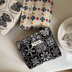 Detail of embroidered canvas makeup bags with butterfly and floral patterns on table