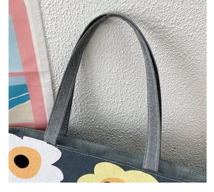 Detailed close-up of the canvas tote handle featuring vibrant yellow and white floral patterns