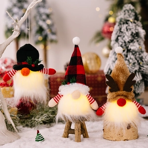Close-up of glowing Christmas gnomes with reindeer antlers and hats in a snowy scene