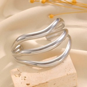 Détail d'un bracelet manchette ondulé multicouche en acier inoxydable sur pierre mate