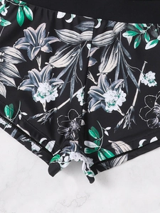 Close-up of women's swim shorts with realistic white lily print on black fabric