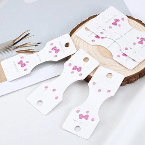 Dettaglio dei cartellini per accessori capelli con fragole e fiocchi rosa su legno