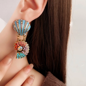 Detailed close-up of vintage-style shell and snail earrings with colorful crystals