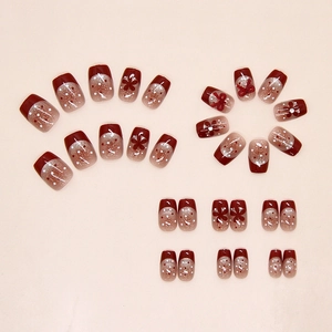Detail of burgundy cat eye press-on nails with white polka dots and floral bow accents