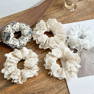 Detailed view of beige and white hollow lace scrunchies in a natural setup
