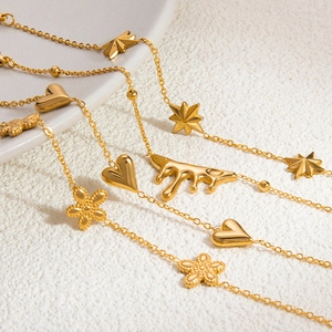 Macro view of 18K gold plated chain bracelets with heart and star charms on textured surface