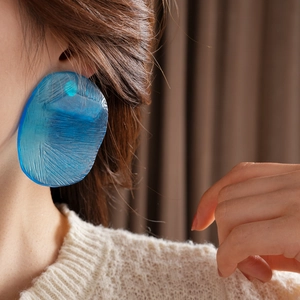Close-up of model wearing large blue irregular resin earring with fine texture