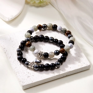 Detail of natural stone couple bracelets with magnetic heart and skull on white silk