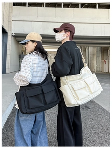 Close-up of black and beige canvas messenger bags with double front pockets for students