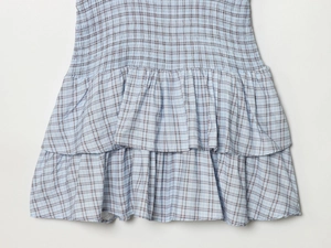 Detail of blue and white plaid dress showing elastic smocked waist and tiered ruffle hem
