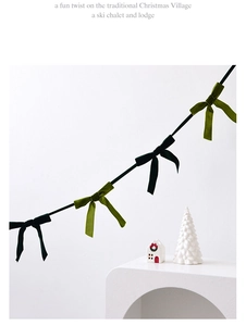 Detail of green velvet bow garland hanging on wall for Christmas tree decoration