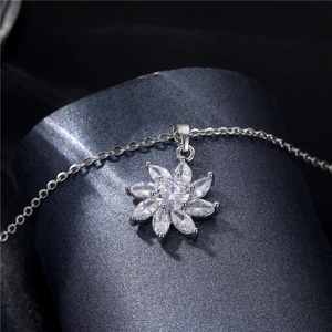 Silver flower pendant necklace with sparkling cubic zirconia on a dark textured surface