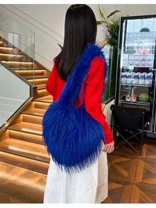 Close-up of blue faux fur shoulder bag with tassel, shown in a lifestyle setting