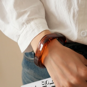 Close-up of a chunky amber resin bangle with a tortoiseshell texture and polished finish