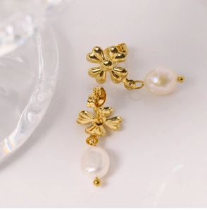 Close-up of golden clover earrings with white pearl pendants on a white background