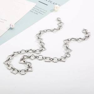 Detail of silver geometric chain necklace with square links and gear-shaped rings