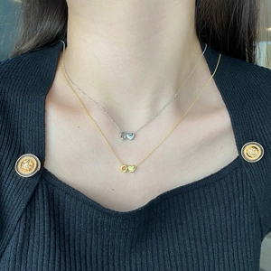Detail of gold and silver S925 necklaces with heart pendants on a model's neck