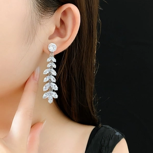 Close-up of sparkling leaf-shaped zircon long tassel earrings on a professional model