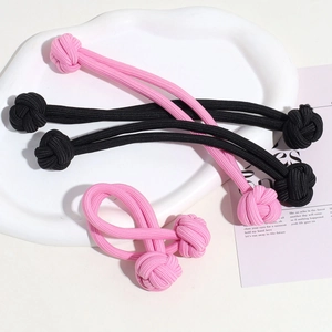 Close-up of five pink and black elastic hair ties on a white ceramic plate