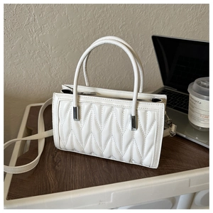 Detailed close-up of a white quilted handbag with diamond patterns and silver hardware