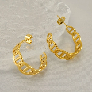 Detail view of golden chain-link hoop earrings on a decorative ice-cracked base