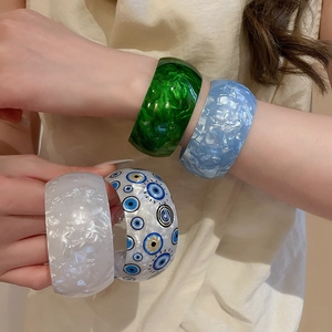 Close-up of stacked acrylic bangles featuring marble textures and blue evil eye pattern